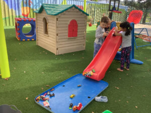 hildren enjoying outdoor play with toys and a slide at the best early learning center in Seven Hills.
