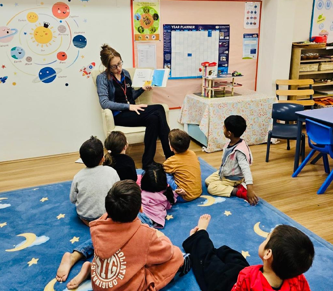 Educator reading a story to young children during reading time at our modern childcare centre in Seven Hills, fostering imagination and early literacy skills.